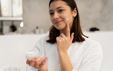 young-woman-applying-moisturizer-her-face-before-taking-bath 1